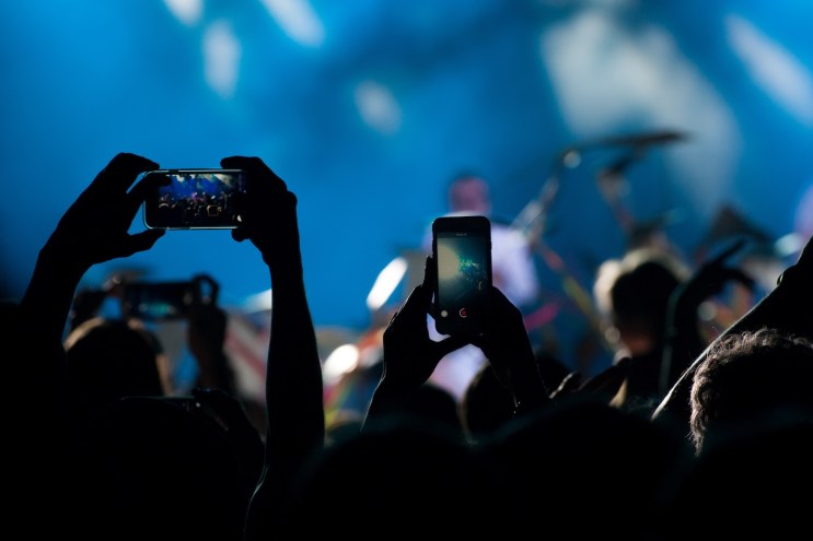 People holding up phones recording a concert
