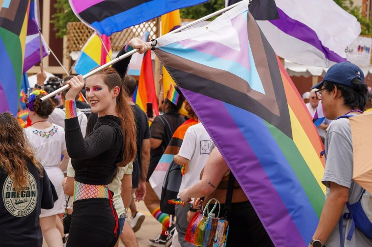 Person carrying the LGBTQ+ Pride flag during a Pride Parade in Dallas