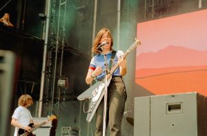 Ratboys frontwoman Julia Steiner performs on stage in red, white and blue shirt with a dark blue axe guitar