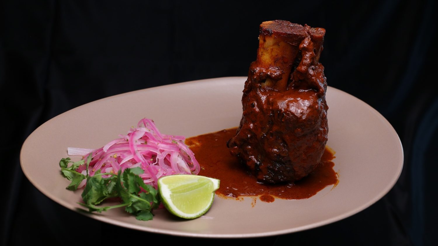 Chamorro en adobo at Manny's Mexican Kitchen, a dish of pork shank in a brick-red adobo sauce