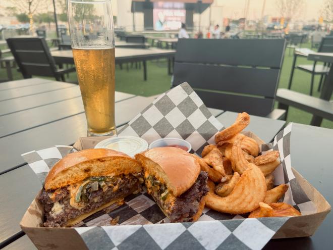 a cheeseburger and beer on a table in Rollertown Brewery's Courtyard.