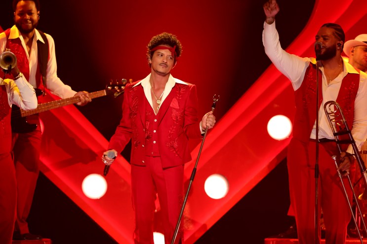 Bruno Mars performs on stage in an all-red suit with microphone stand in hand at the grammys
