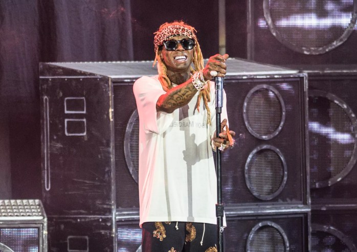 lil wayne stands on stage at house of blues wearing sunglasses and a white shirt while holding a mic toward the crowd