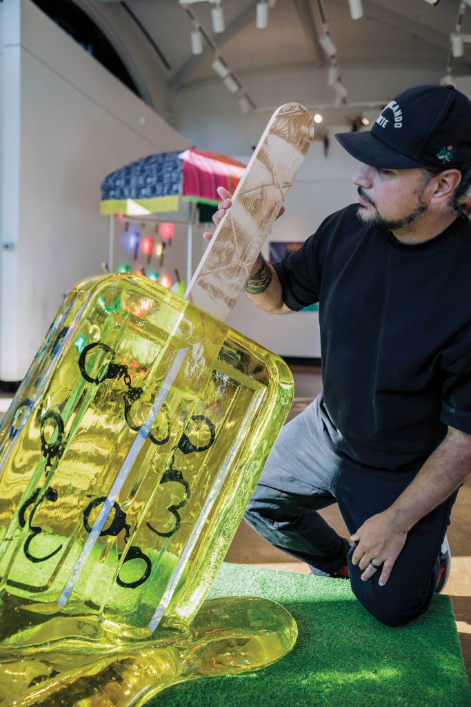Artist Victor Quiñonez poses with his artwork: a melting paleta infused with handcuffs.