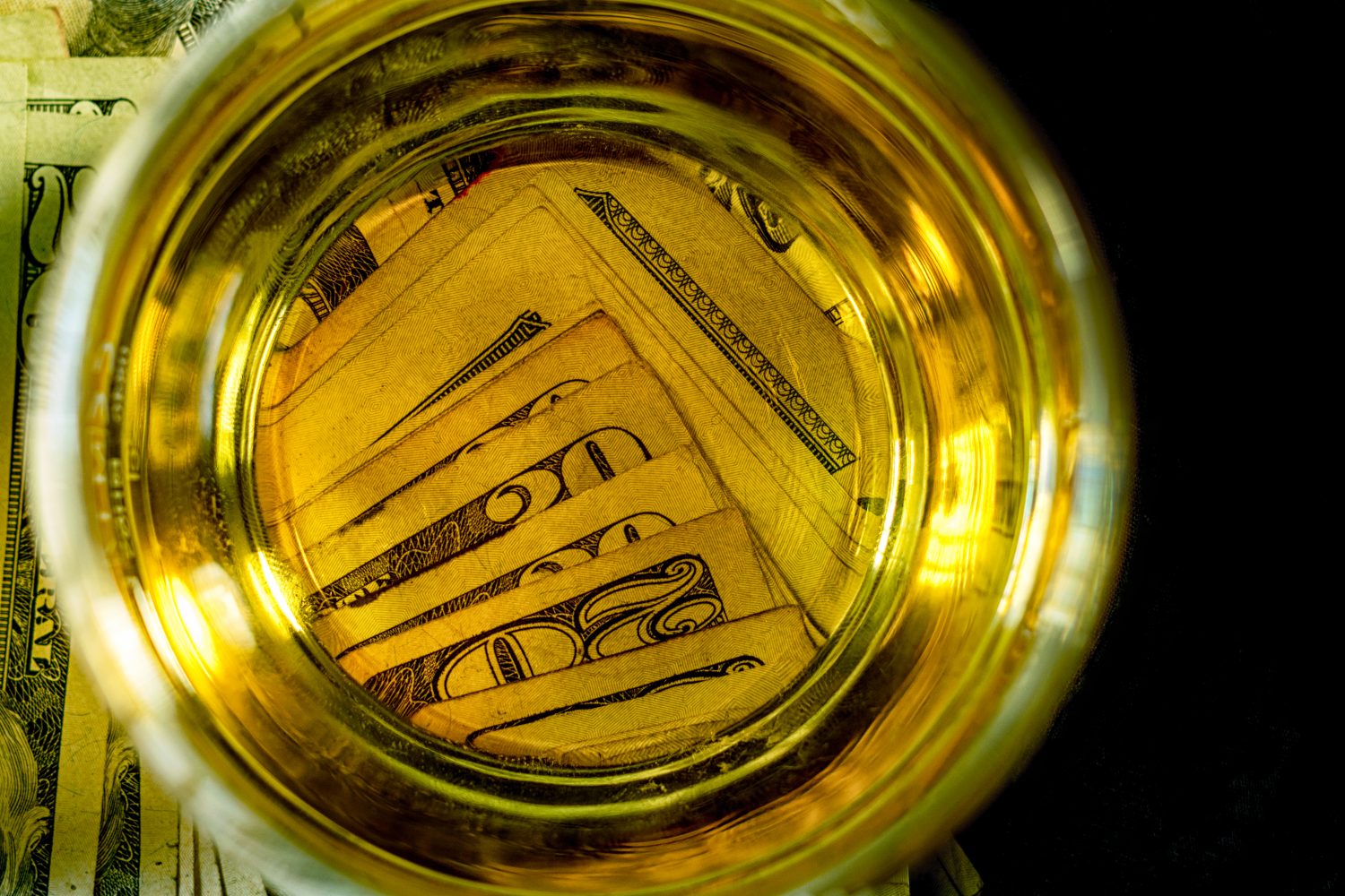Twenty dollar bills at beneath the bottom of a beer glass.