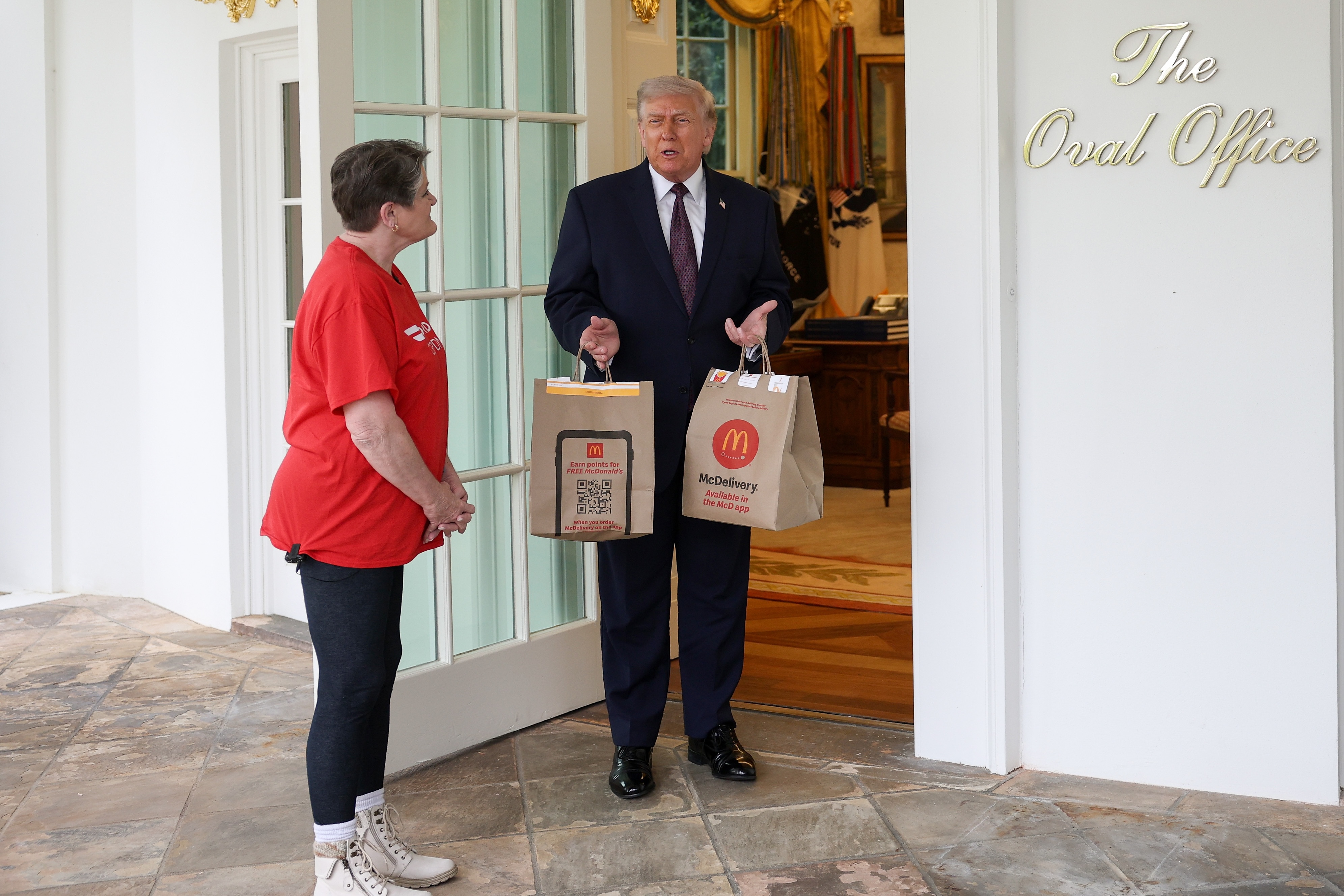 resident Donald Trump receives a DoorDash delivery of McDonald's from Sharon Simmons before he speaks to the press during an event outside the Oval Office of the White House on April 13, 2026 in Washington, DC.
