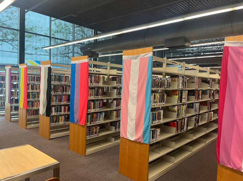 Bookshelves housing special collections at the Oak Lawn Library decorated with pride flags.