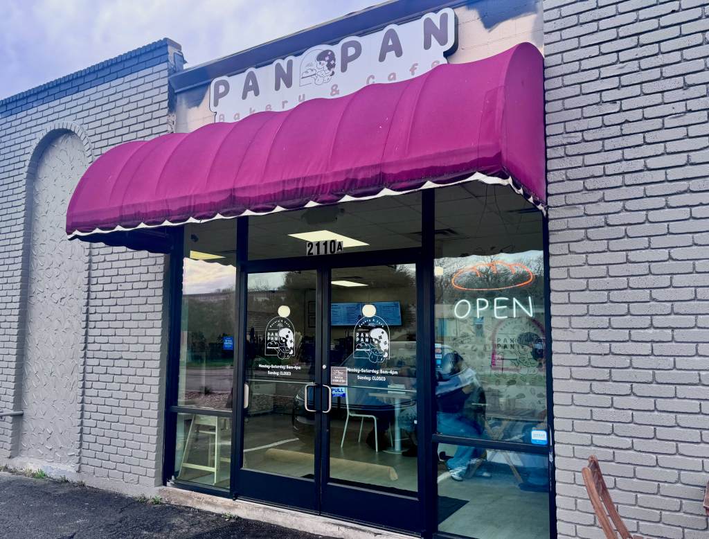The exterior of PanPan cafe, with a maroon awning over the door.