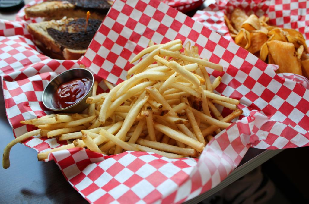 Seegars french fries in a basket with ketchup.