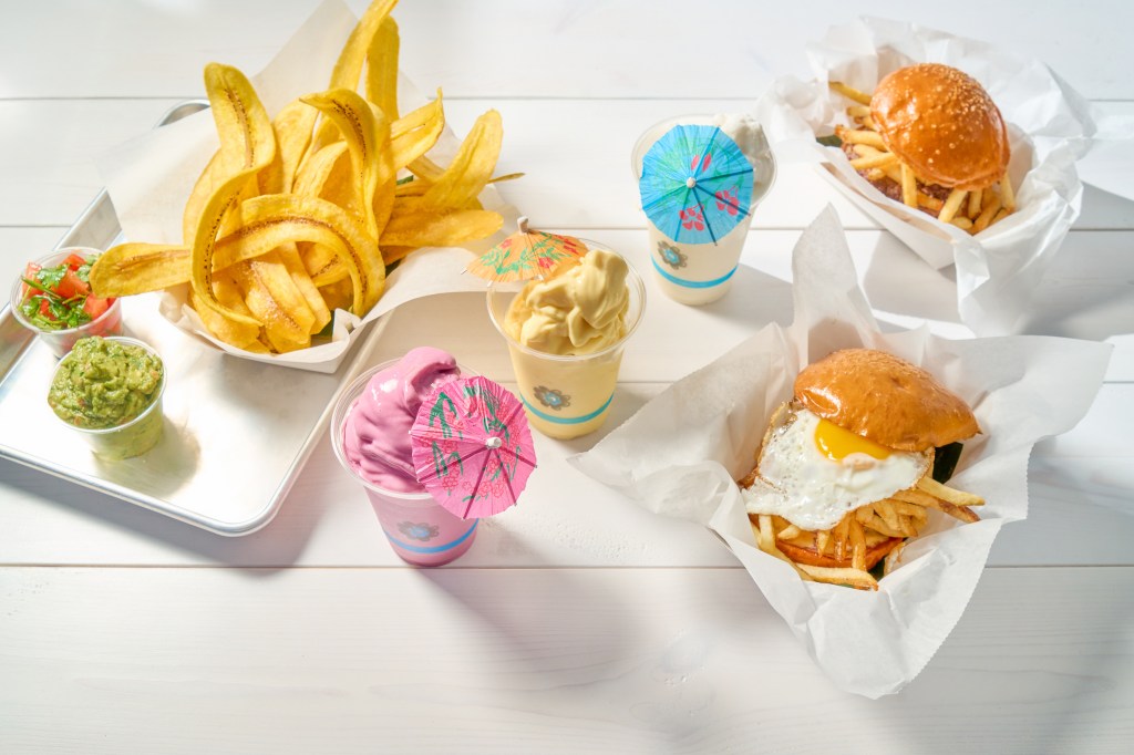 Frita Batidos signature Cuban street food spread with burgers, crispy fries, fried sweet plantains, tropical milkshakes, and fresh sides of guacamole and pico de gallo.