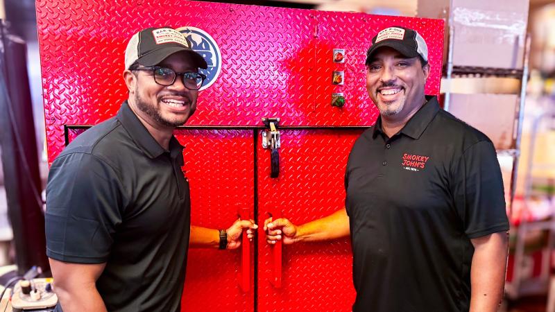 Brent and Juan Reaves next to a barbecue smoker