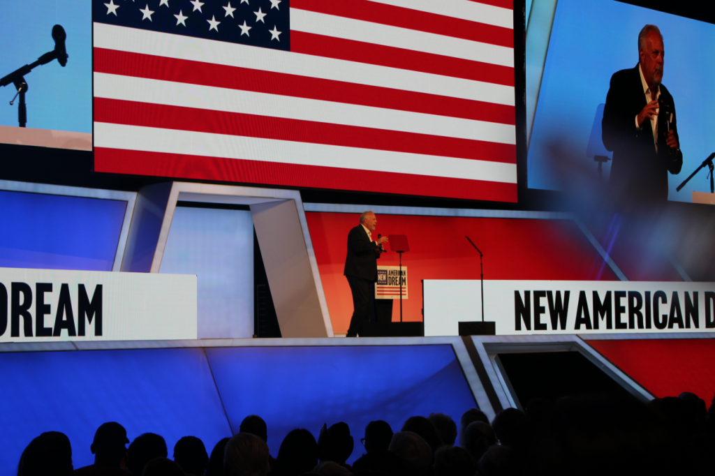 Arlington Mayor Jim Ross introduces Talarico on stage with American Flag in background.