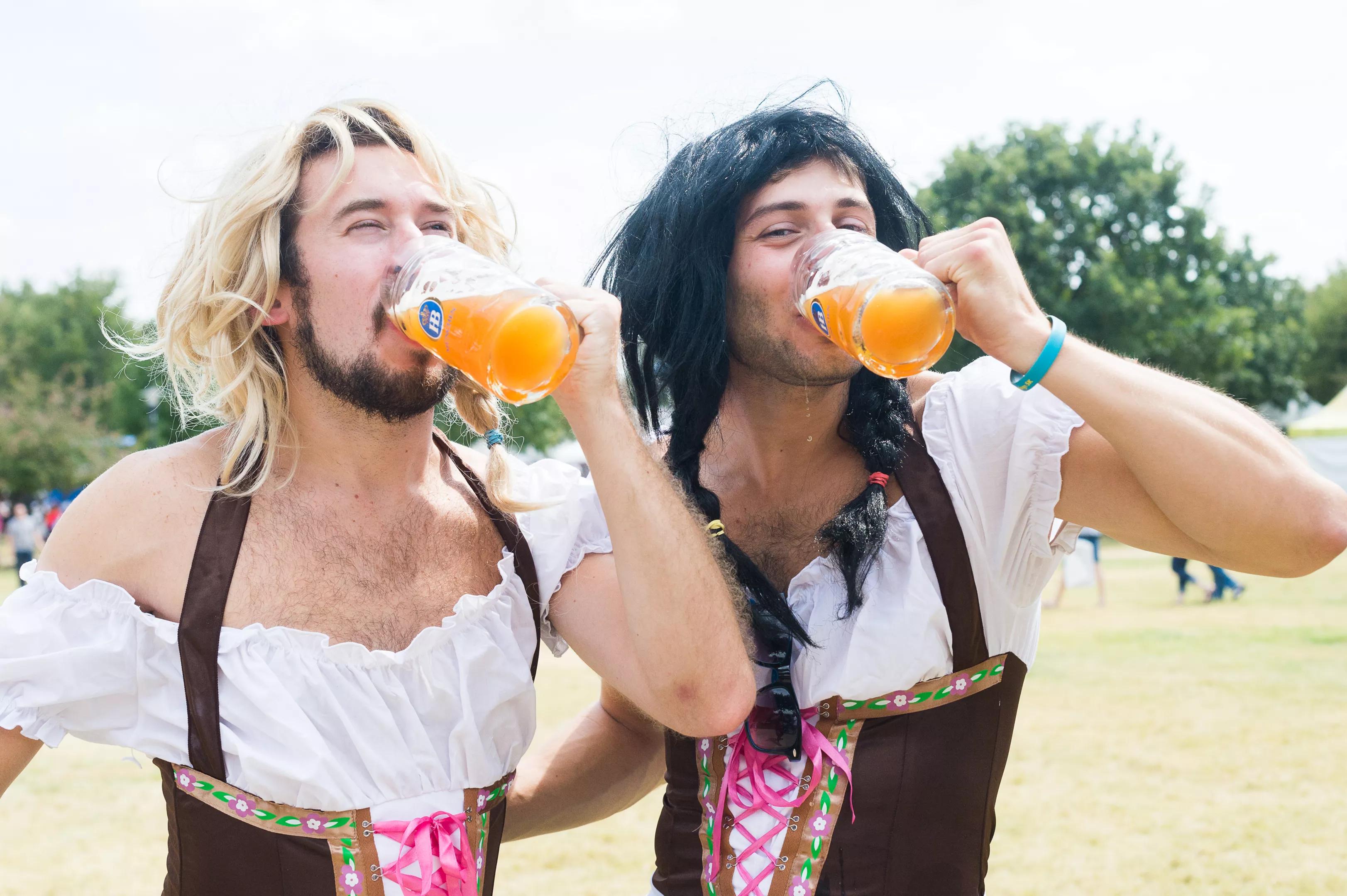 Two men wearing traditional German outfits drinking beer.