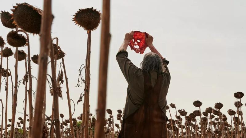 Leatherface from Texas Chain Saw Massacre holds a mask in the air. The character is one of Texas' biggest legends.