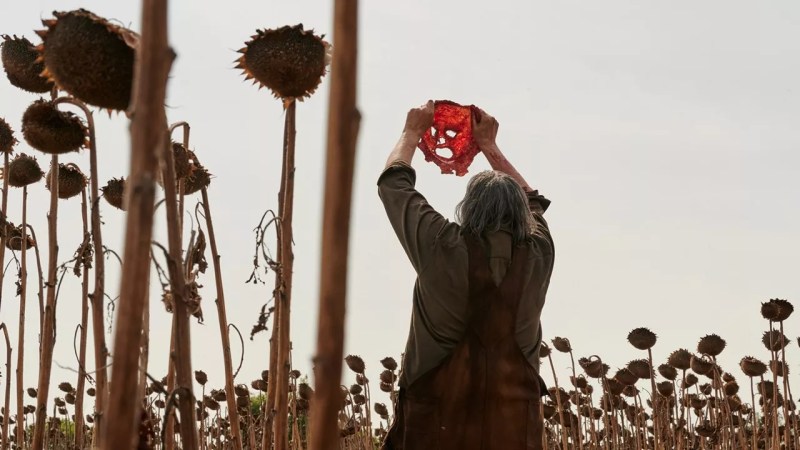 Leatherface from Texas Chain Saw Massacre holds a mask in the air. The character is one of Texas' biggest legends.