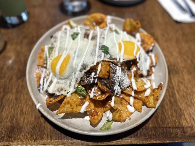 a big bowl of chilaquiles on a wooden table.